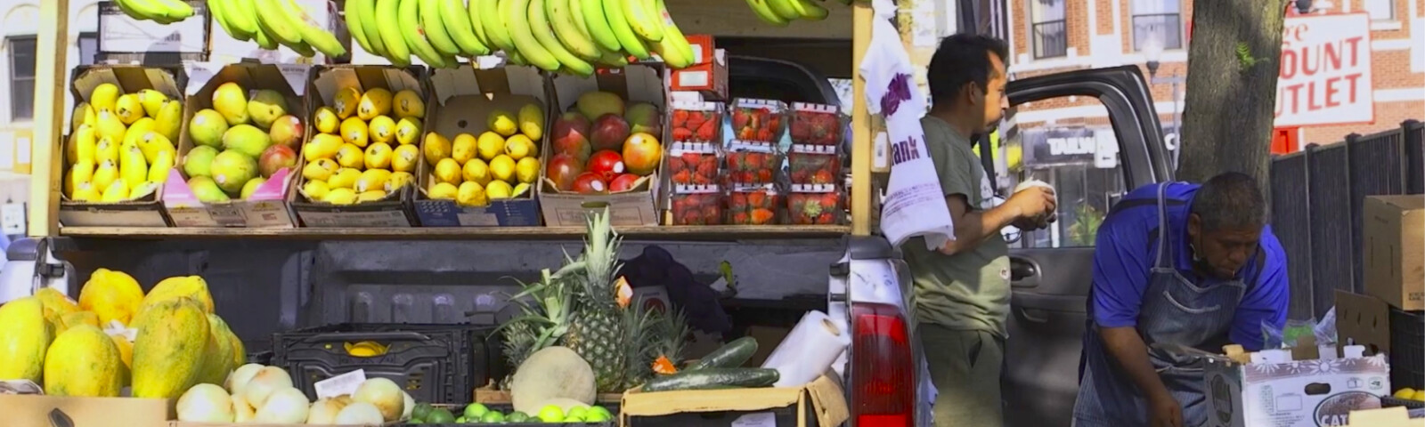A vendor arranging fruit and vegetables at an outdoor stand in Albany Park